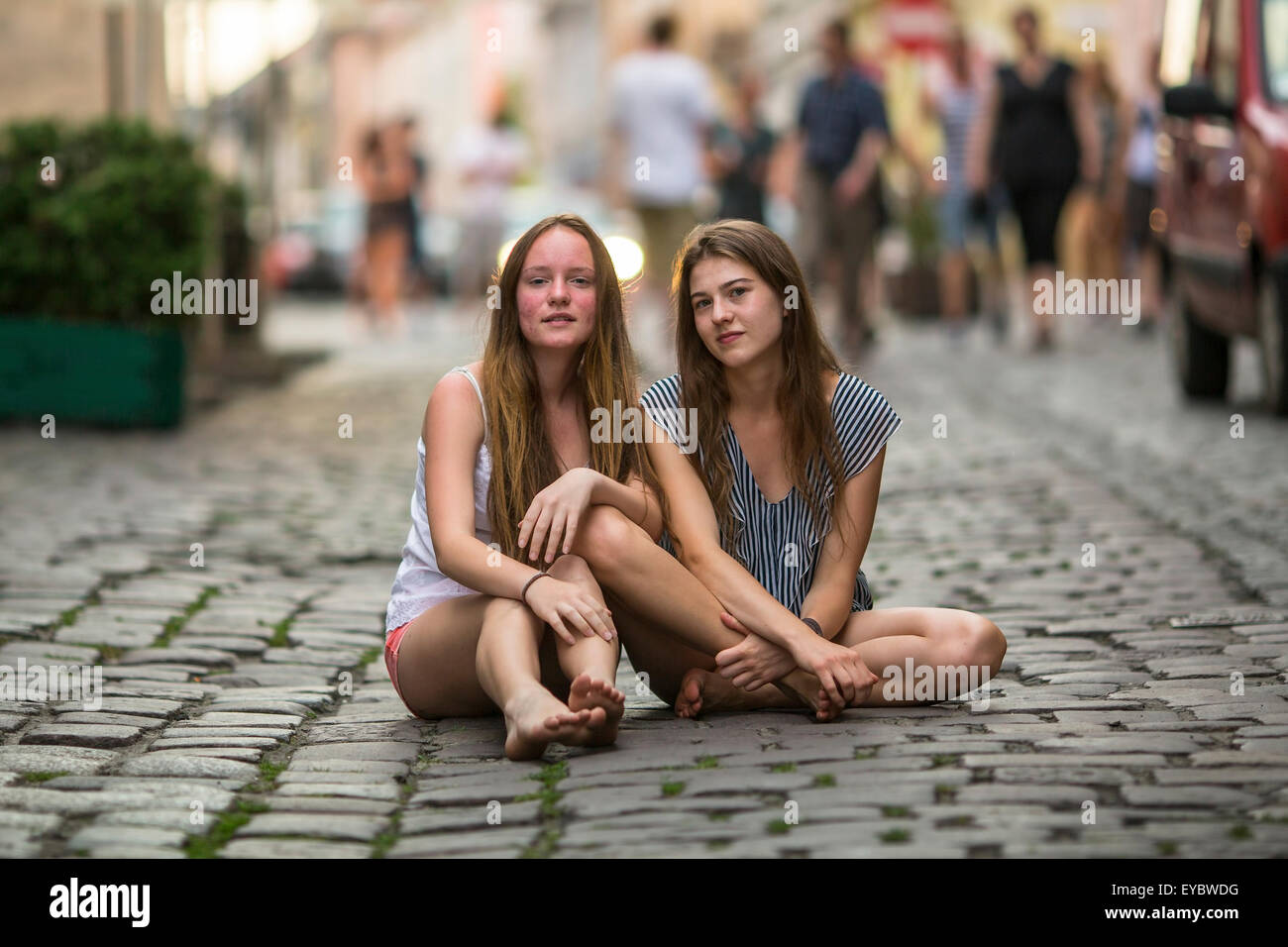 Zwei süße junge Mädchen sitzen zusammen auf das Steinpflaster. Stockfoto