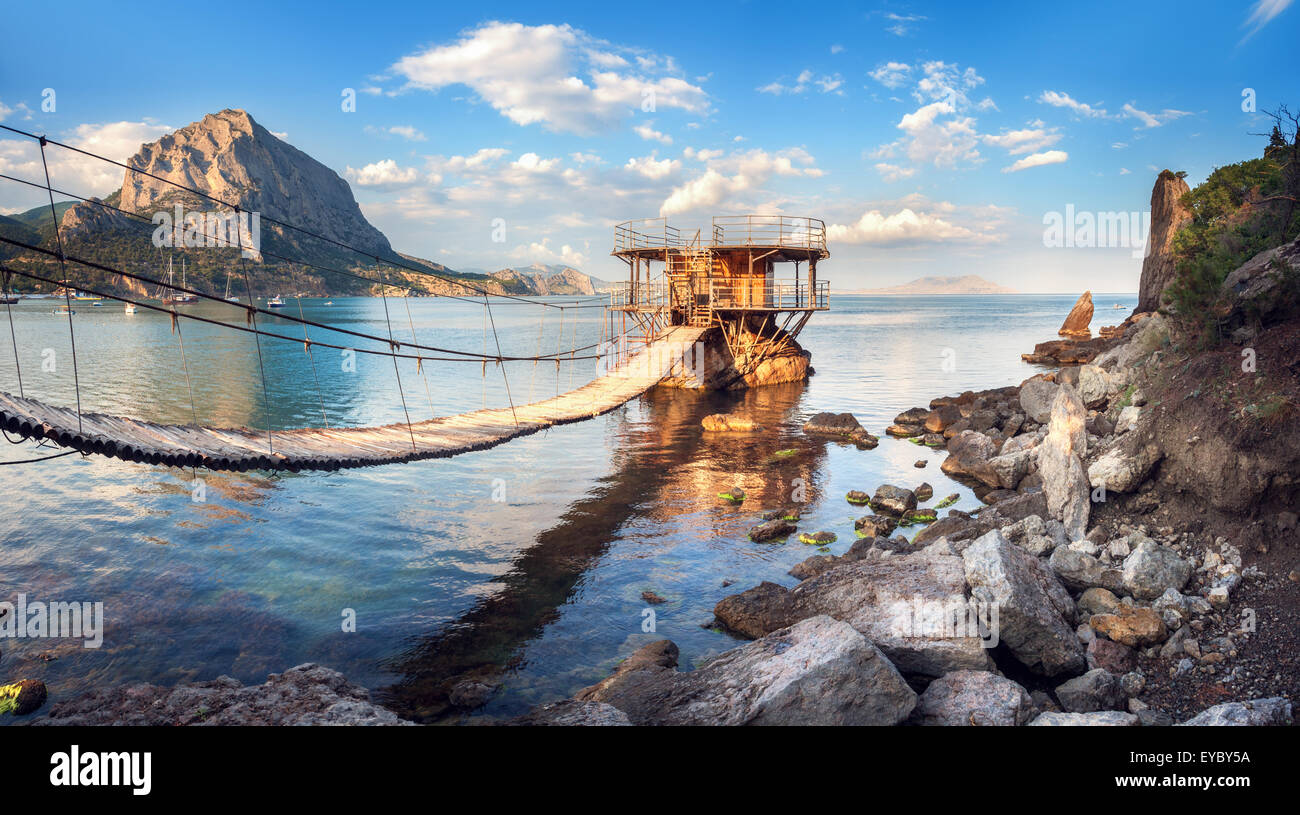 Schönen Sommer Sonnenuntergang am Meer mit Brückenbau, Berge und Steinen auf der Krim Stockfoto