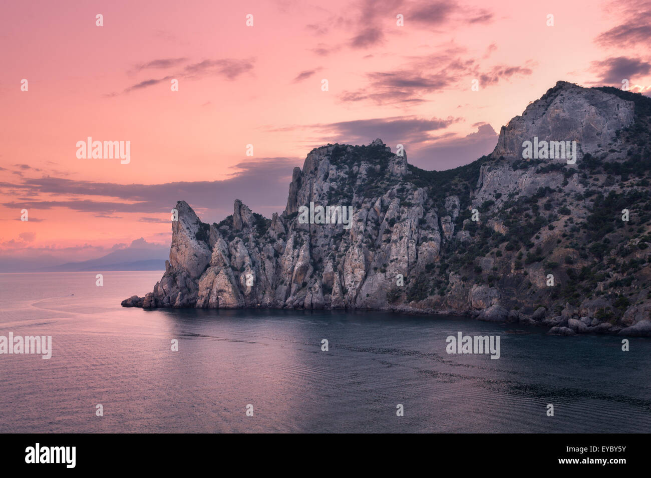 Schönen Sommer Sonnenuntergang am Meer mit Bergen, Steinen, Bäumen und bewölktem Himmel auf der Krim. Dämmerung, Dämmerung. Stockfoto