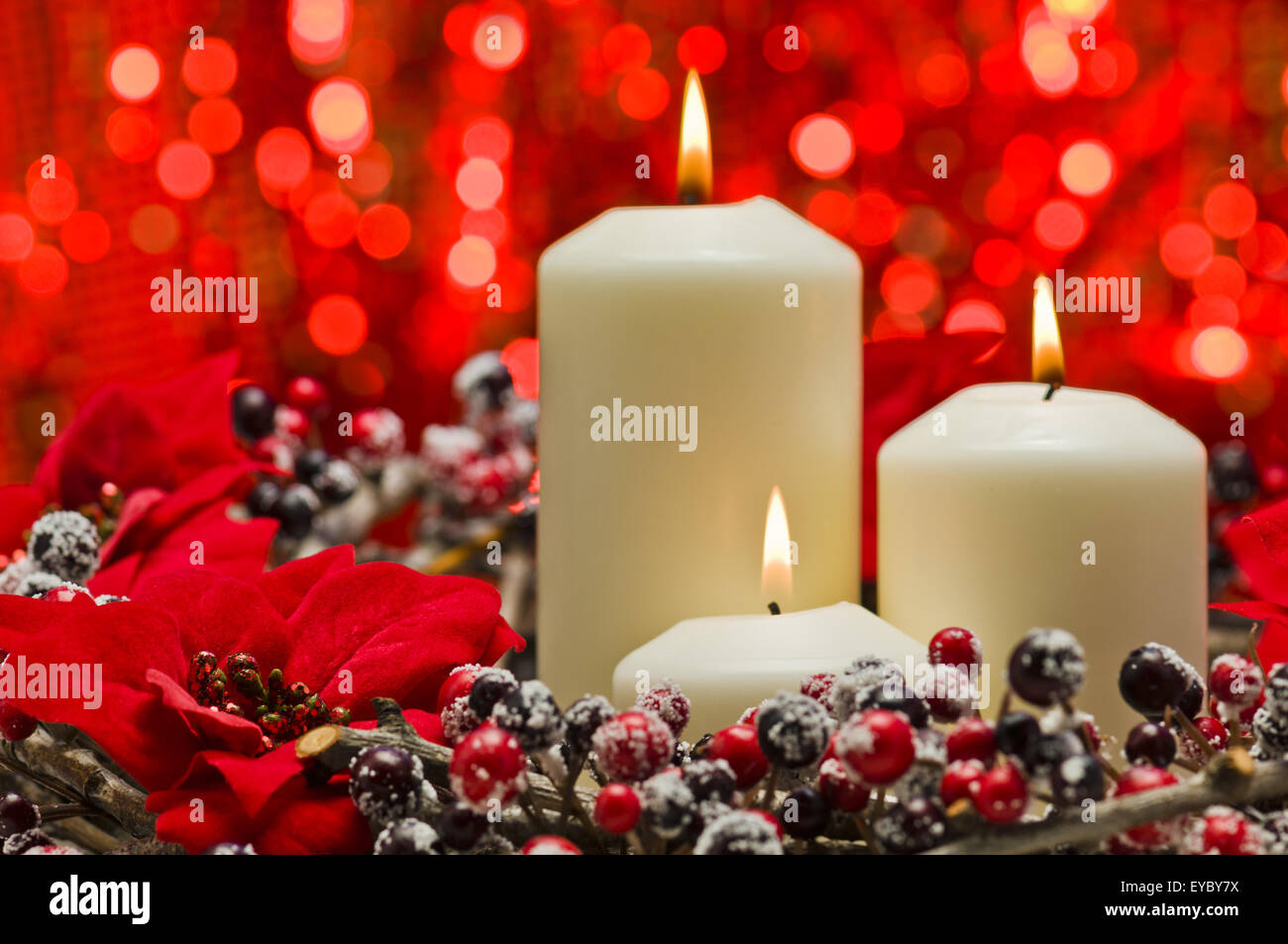 Weiße Kerzen in der Herbst-Winter-Dekoration vor einem roten Hintergrund Stockfoto