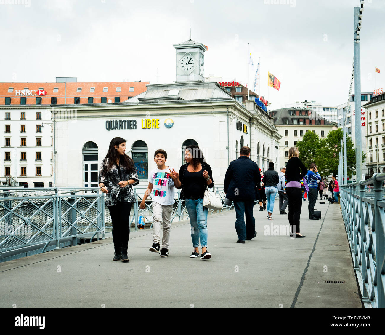 Junge Menschen gehen über eine Brücke in Genf, Schweiz, mit dem Slogan Quartier Libre, was bedeutet "Freie Zeit", dahinter Stockfoto