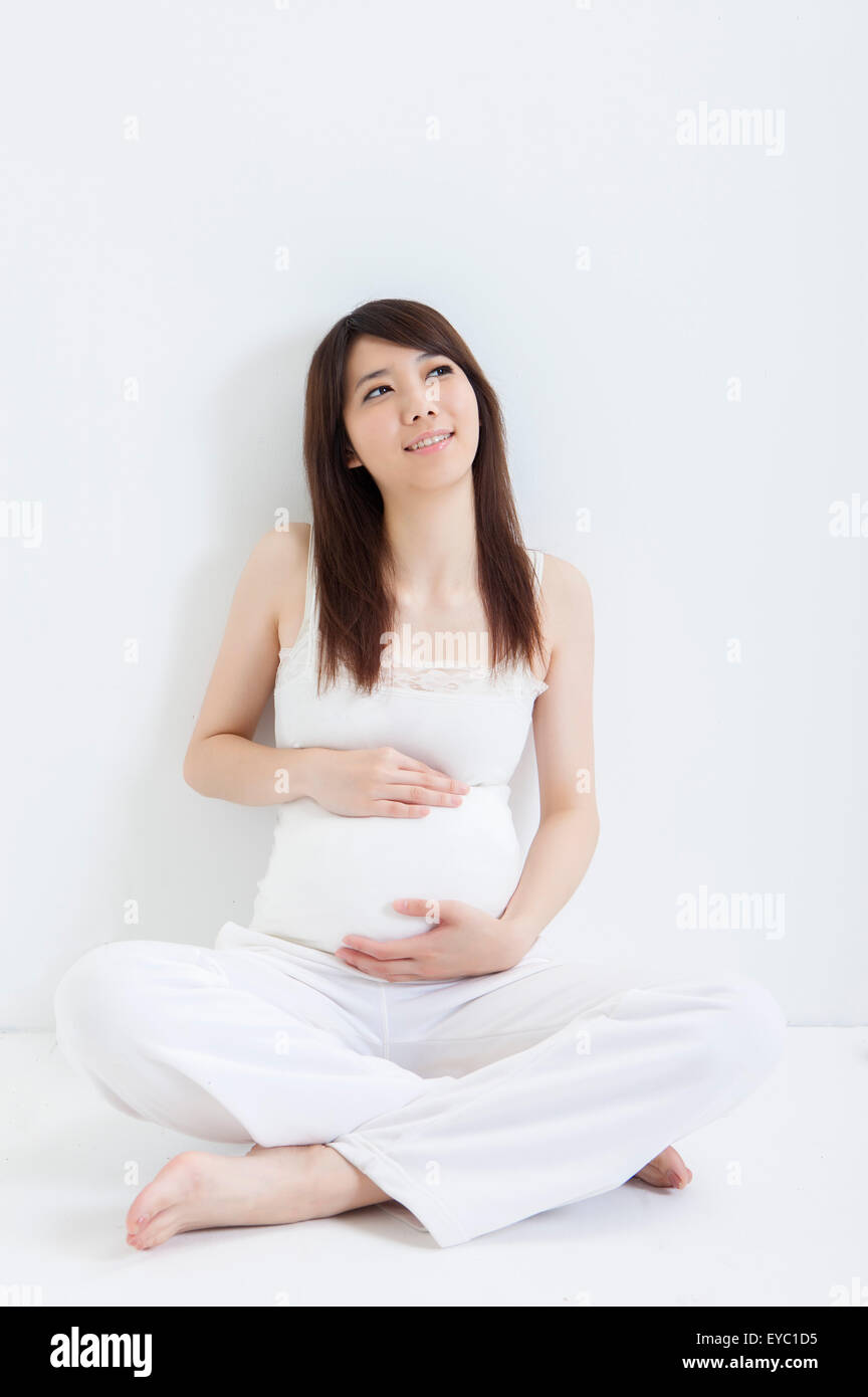Schwangere Frau mit Händen am Bauch nachschlagen, Stockfoto