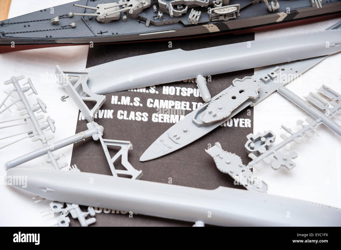 Italeri Modell Kunststoff Kriegsschiff Kit. Satz Teile auf die Anweisungen unter anspornen. Hintergrund ist ein fertig lackiert Modell der Deutschen Schlachtschiff. Stockfoto