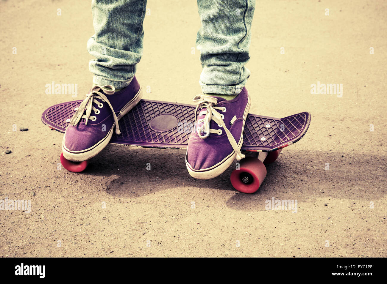 Teenager Füße in Jeans und Detektive auf einem Skateboard, Foto mit warmen Retro-Tonwertkorrektur, alten Stil Stockfoto