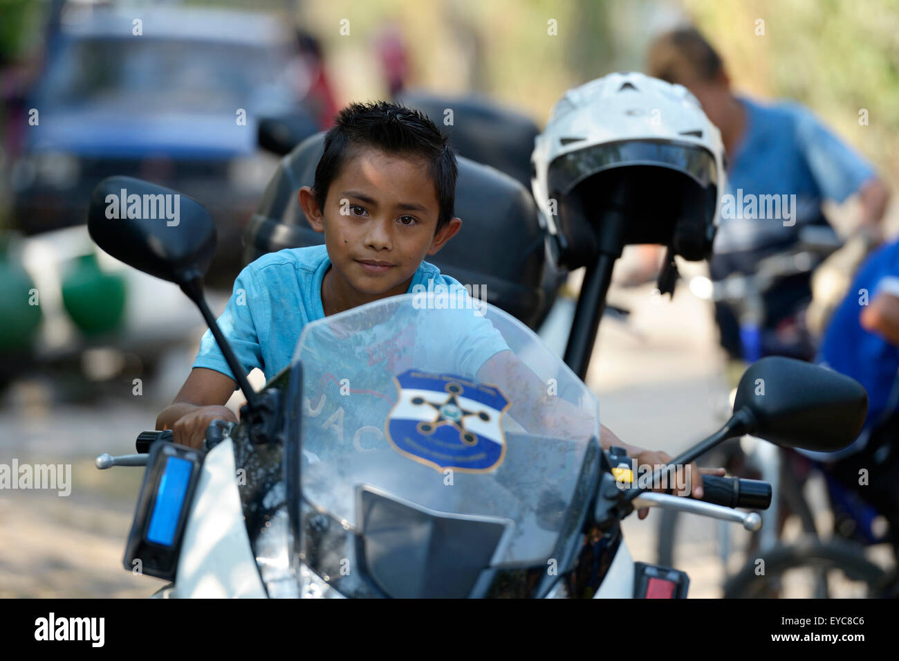 Junge auf einem Polizeimotorrad bei einer Friedensinitiative von der Polizei und der katholischen Kirche in den Slums von Colonia Monsenor Romero Stockfoto
