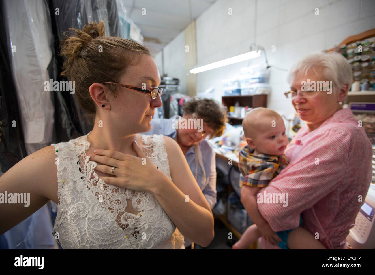 Broomfield, Colorado - Eine junge Frau wird mit einer Hochzeit Kleid ausgestattet, während ihre Mutter ihr Baby hält. Stockfoto