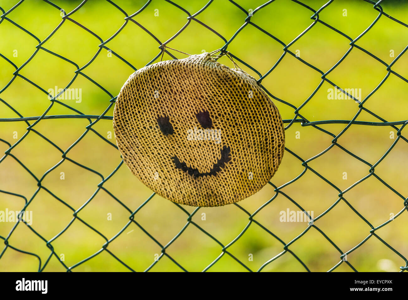 Gestrickte Smiley-Gesicht fixiert auf kabelgebundene Zaun Stockfoto