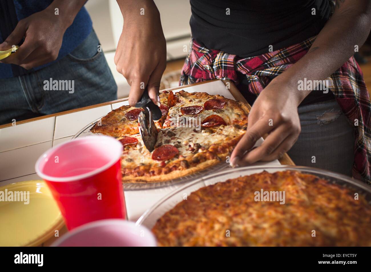 Nahaufnahme der Womans Hände schneiden Pizza in der Küche zugeschnitten Stockfoto