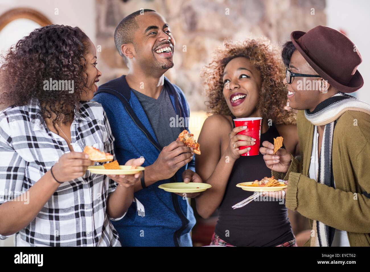 Vier Erwachsene Freunde lachen und Essen Party Essen in der Küche Stockfoto