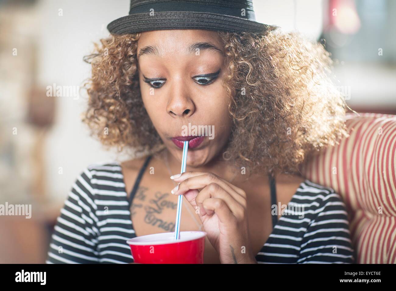 Porträt der jungen Frau ein Gesicht ziehen, während alkoholfreies Getränk trinken Stockfoto