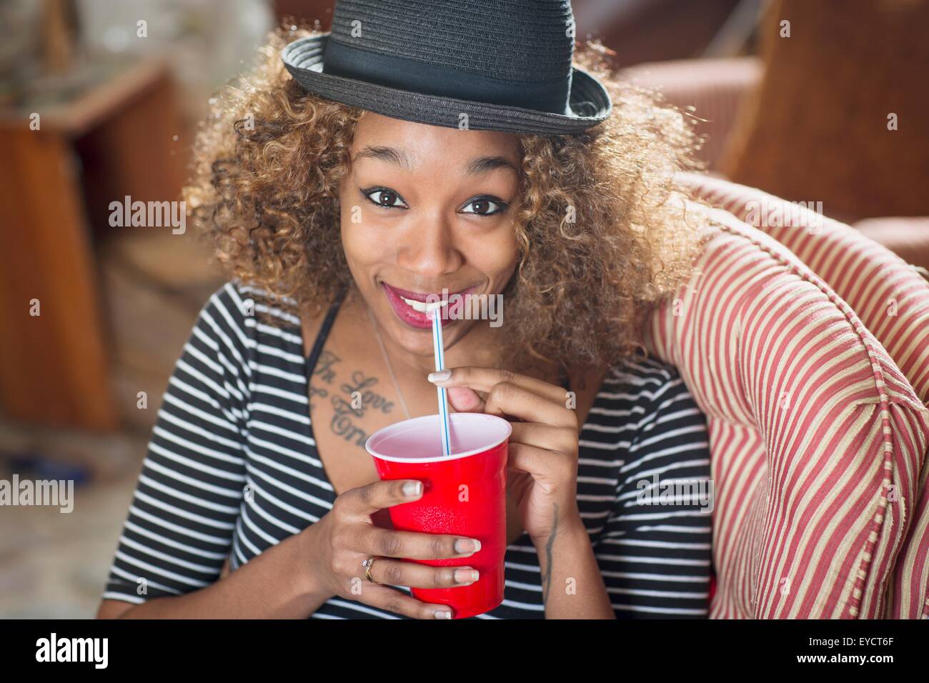 Porträt der jungen Frau trägt Fedora und trinken alkoholfreies Getränk Stockfoto