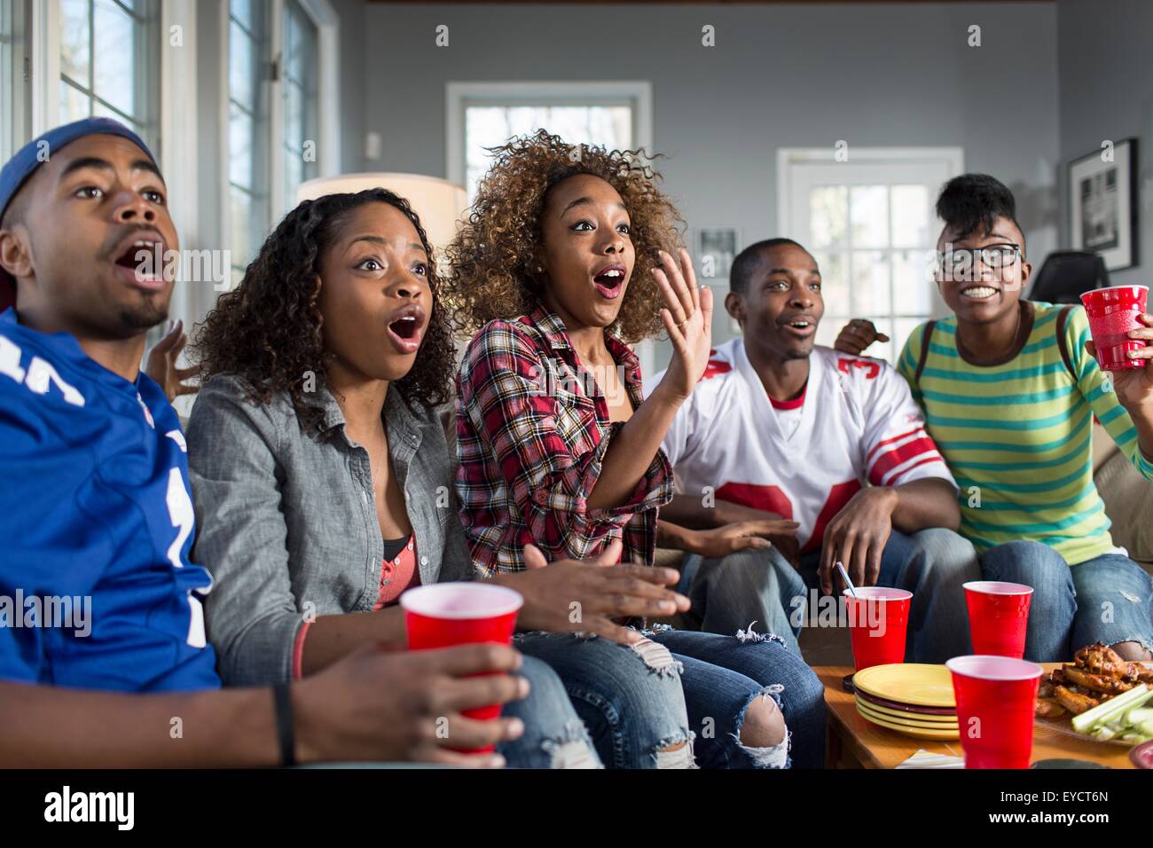Fünf Erwachsene Freunde, keuchend, während des Fernsehens vom sofa Stockfoto