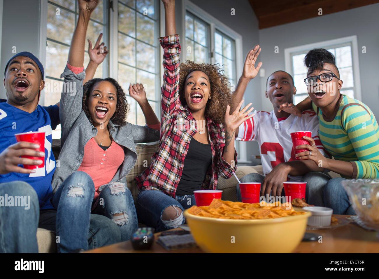 Fünf Erwachsene Freunde feiern während des Fernsehens vom sofa Stockfoto