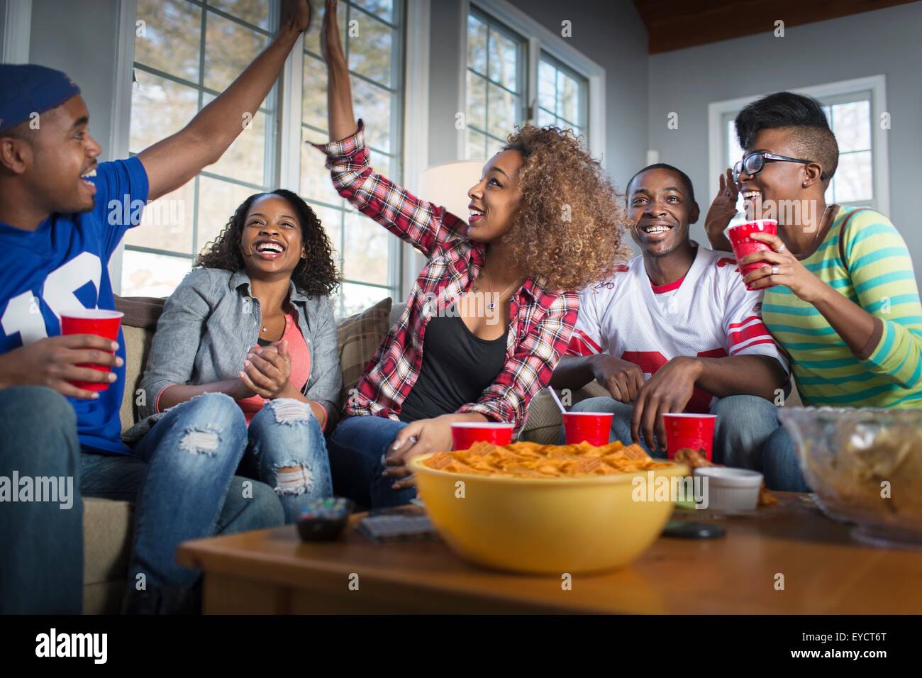 Fünf Erwachsene Freunde feiern mit hohen fünf während des Fernsehens vom sofa Stockfoto