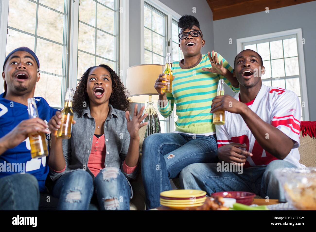 Vier Erwachsene Freunde schnappen offenen Mund während des Fernsehens vom sofa Stockfoto