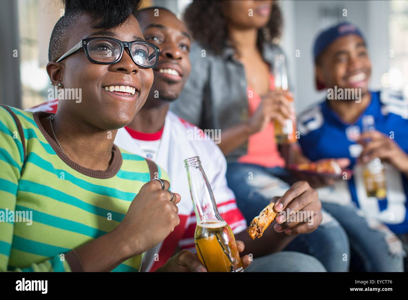 Vier Erwachsene Freunde in Flaschen Bier zu trinken, während des Fernsehens vom sofa Stockfoto
