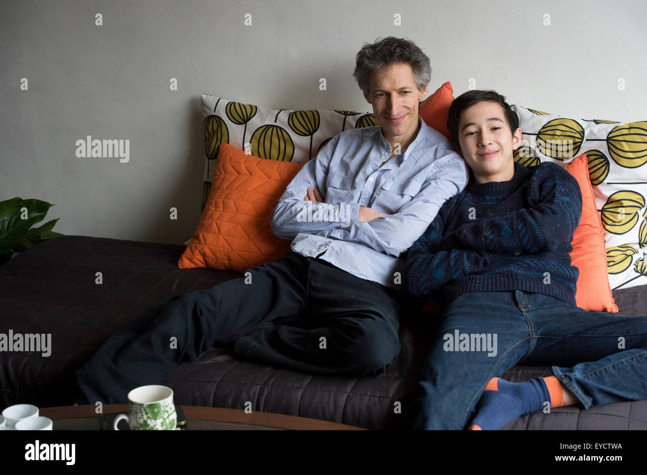 Porträt von Vater und Sohn im Teenageralter entspannend auf sofa Stockfoto