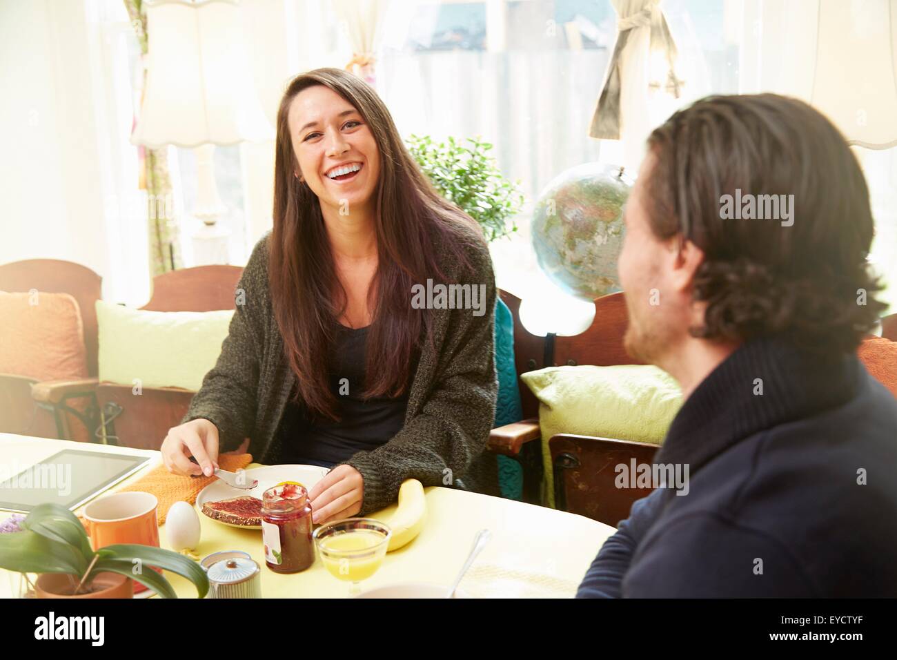 Junges Paar Lachen am Frühstückstisch Stockfoto