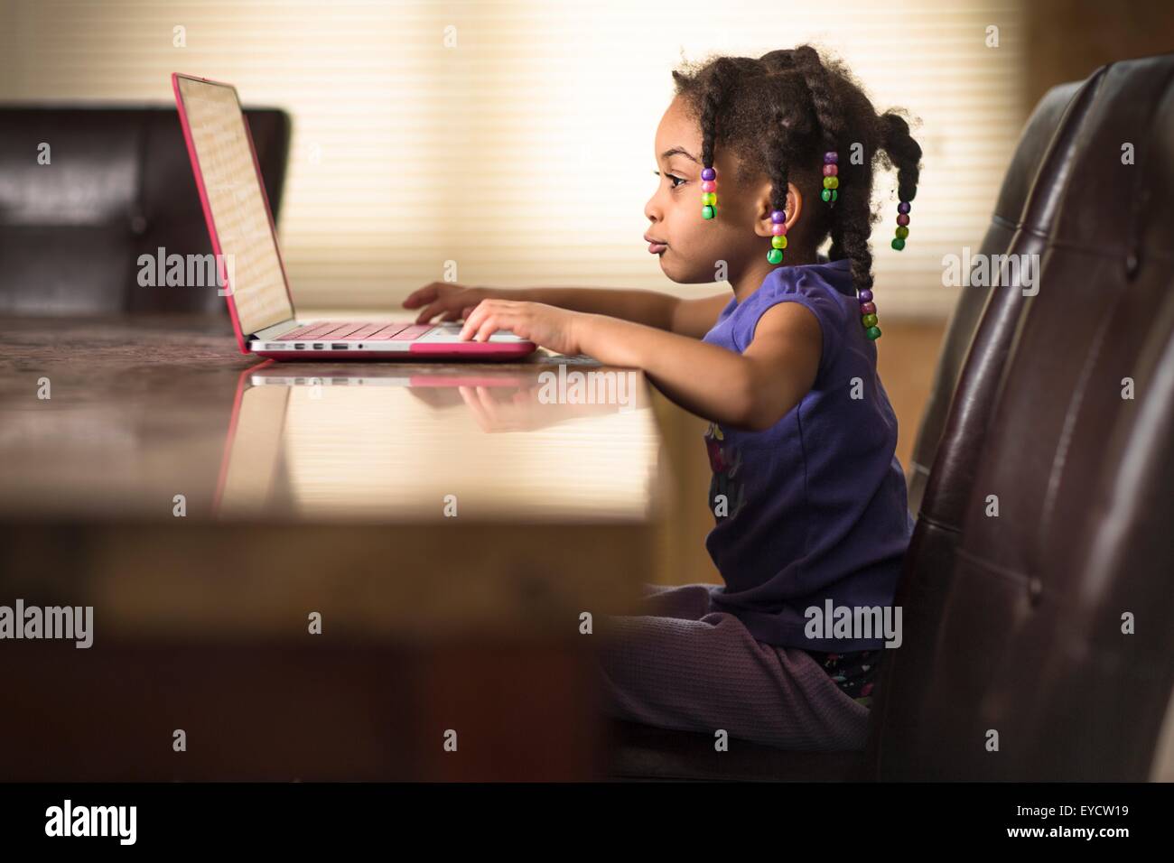 Niedliche Mädchen am Esstisch mit laptop Stockfoto