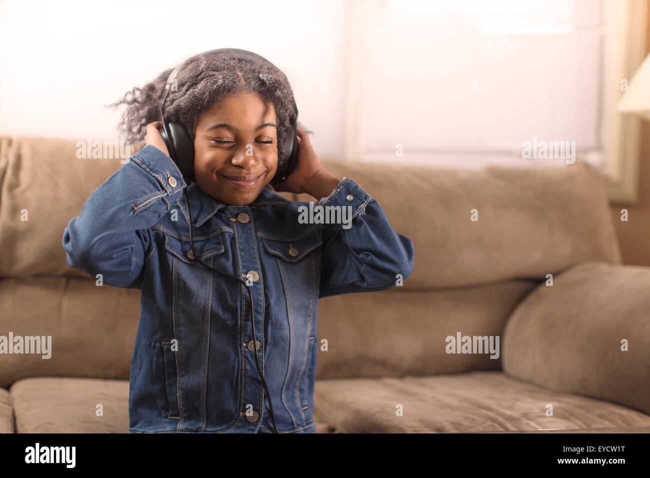 Mädchen mit Augen geschlossen Kopfhörer Musik hören auf sofa Stockfoto