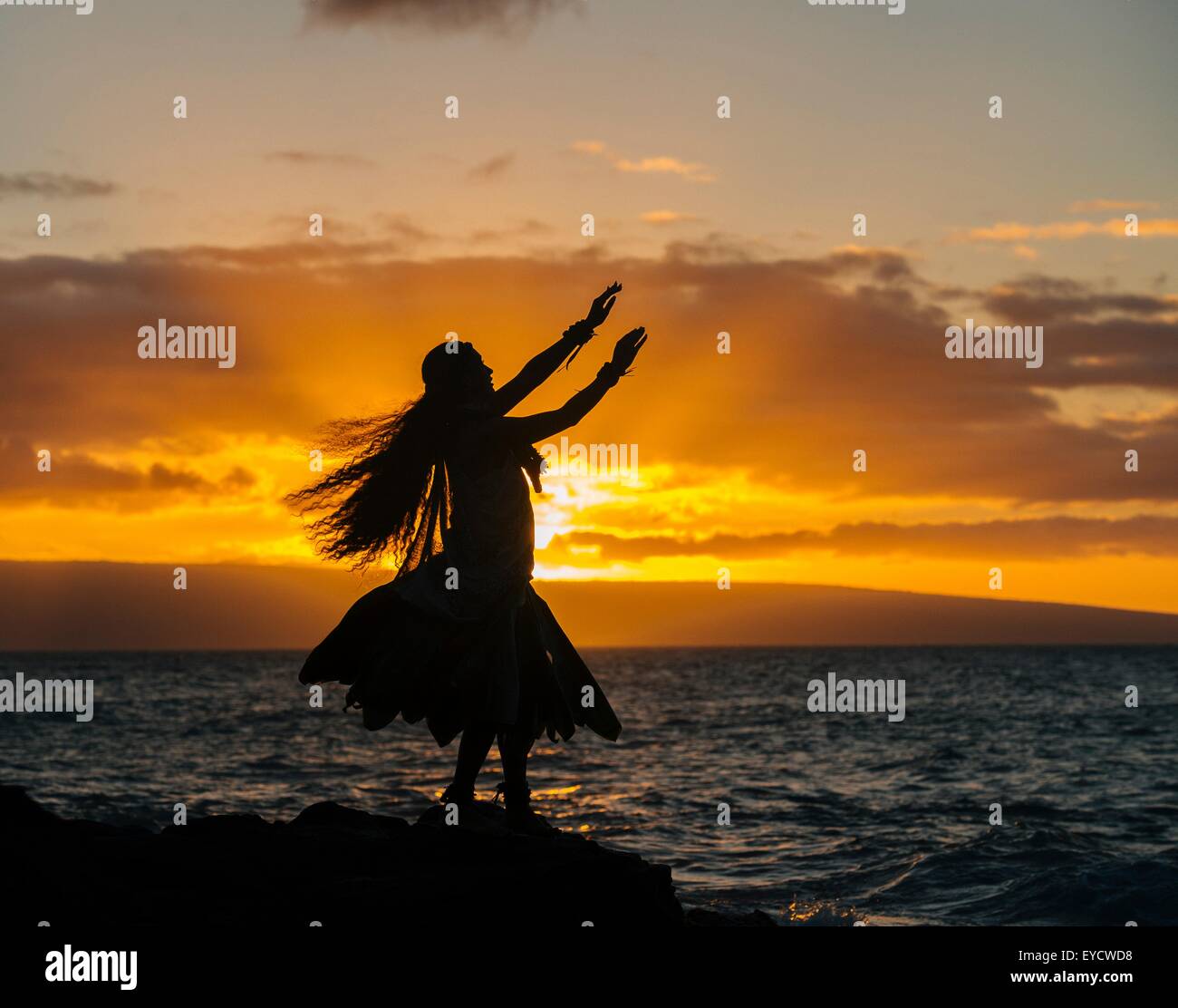 Silhouette junge Frau in Tracht, Hula Tanz auf küstennahen Felsen bei Sonnenuntergang, Maui, Hawaii, USA Stockfoto