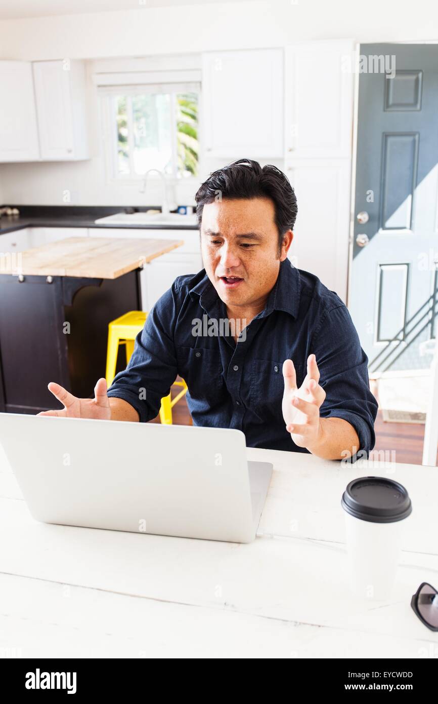 Reife Geschäftsmann mit Händen öffnen arbeiten am Laptop am Küchentisch Stockfoto