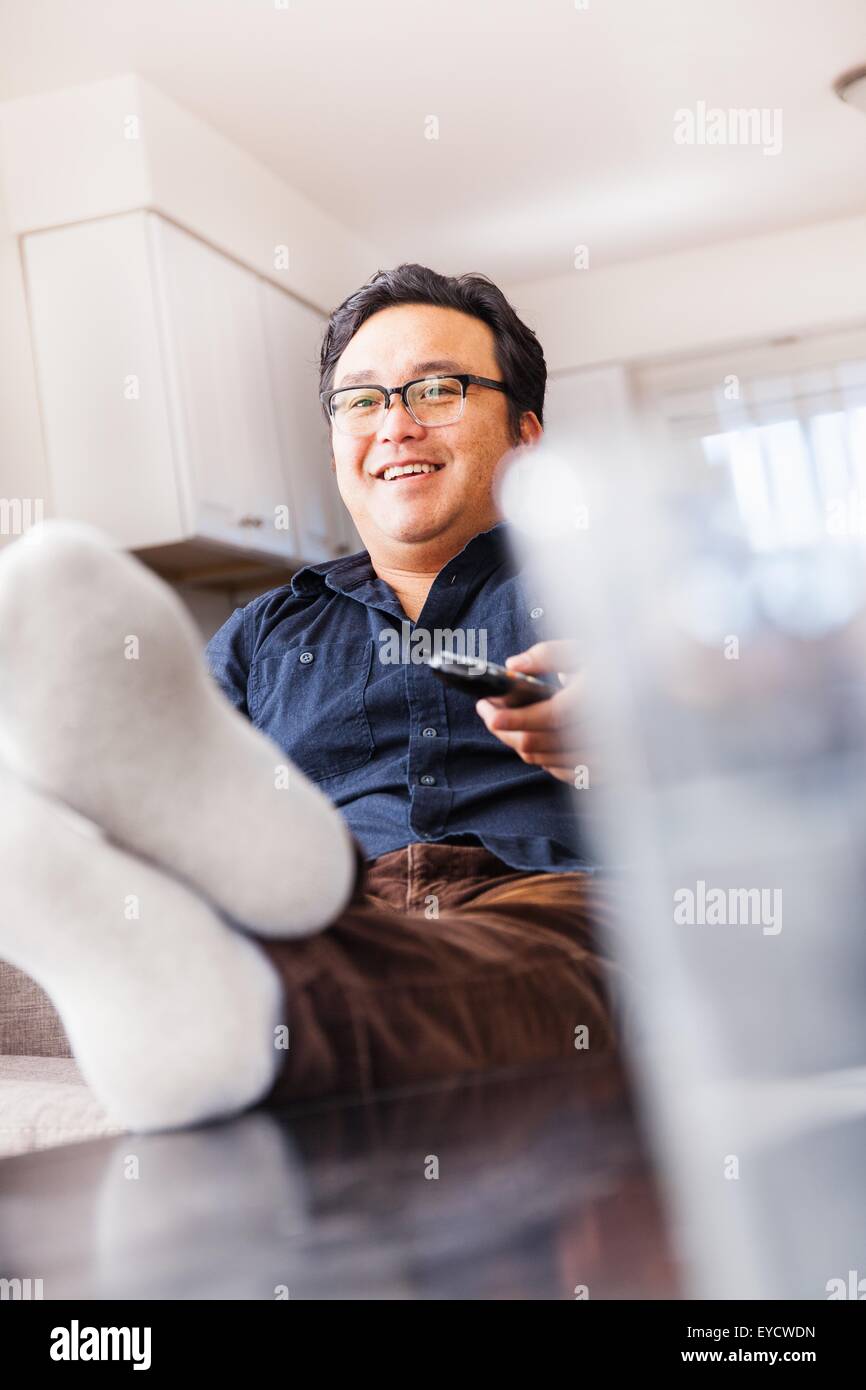 Reifer Mann auf Sofa vor dem Fernseher mit Fernbedienung Stockfoto