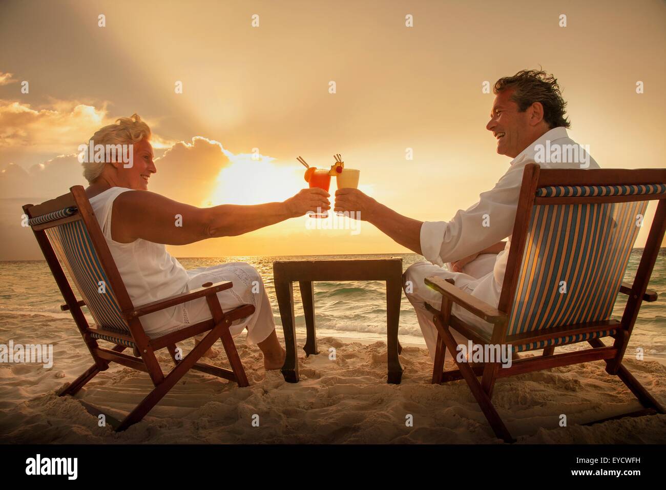 Älteres Paar, toasten Getränke am Strand, Malediven Stockfoto