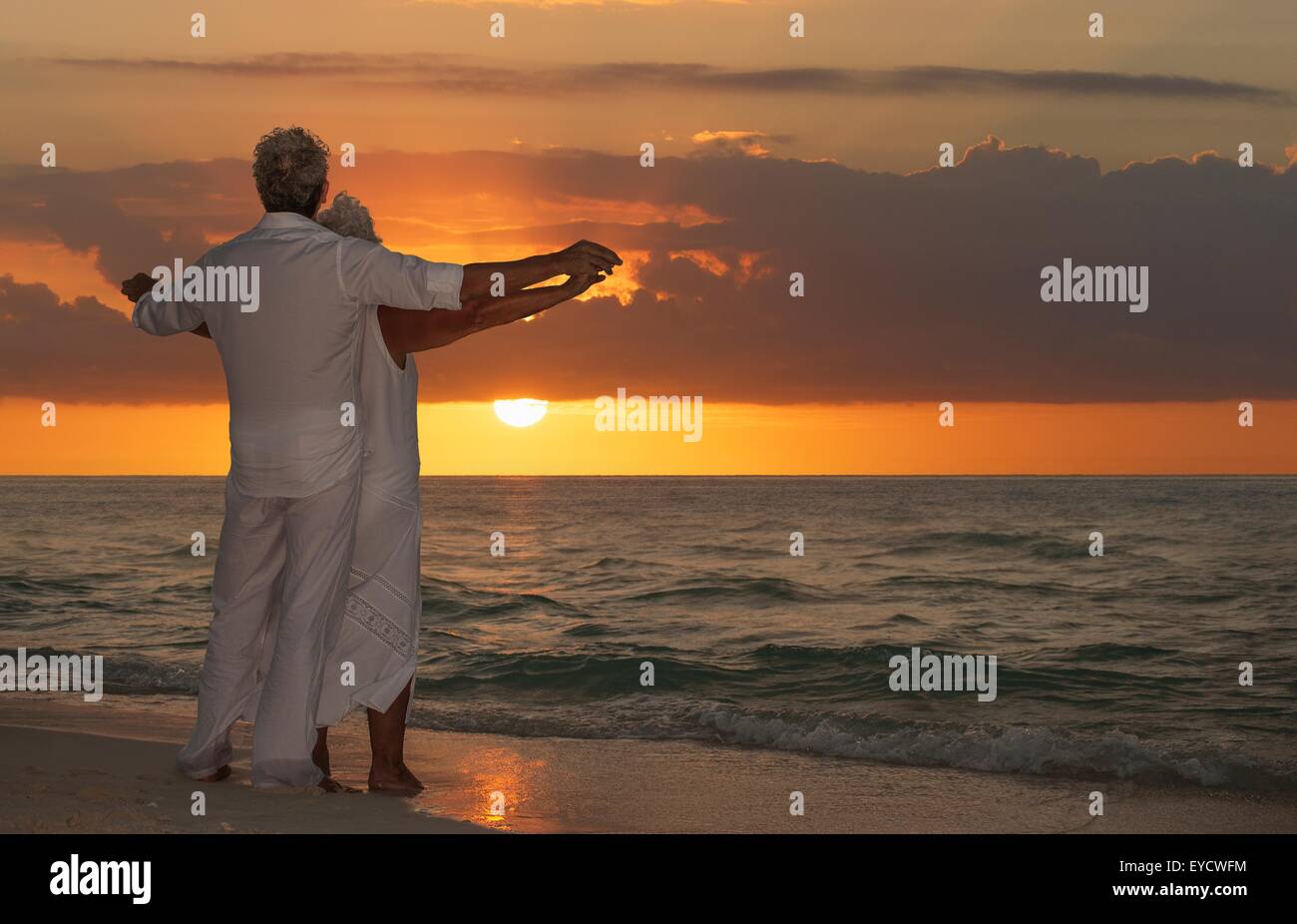 Älteres Paar am Strand bei Sonnenuntergang Stockfoto