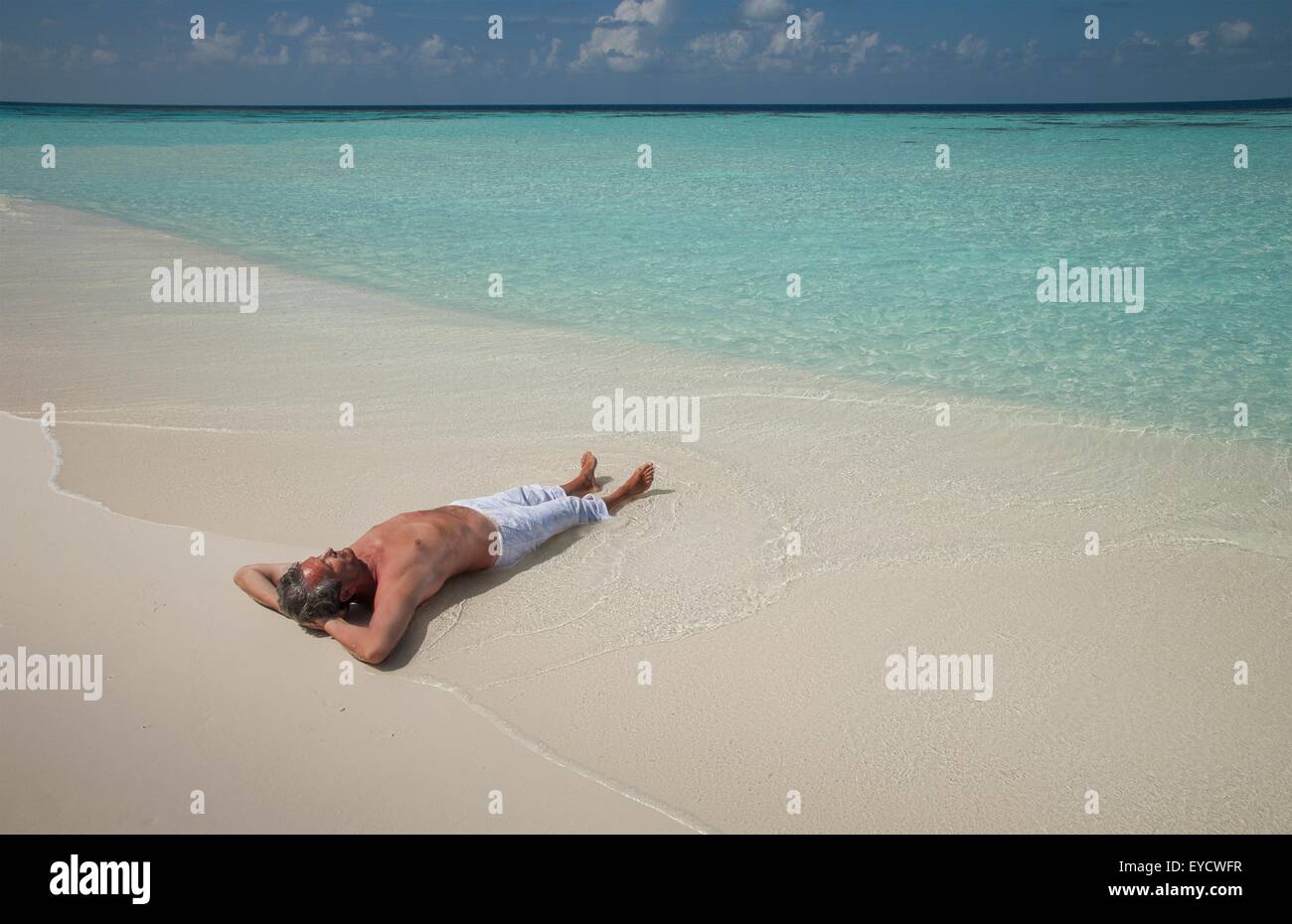 Ältere Mann liegt auf sandigem Strand, Malediven Stockfoto