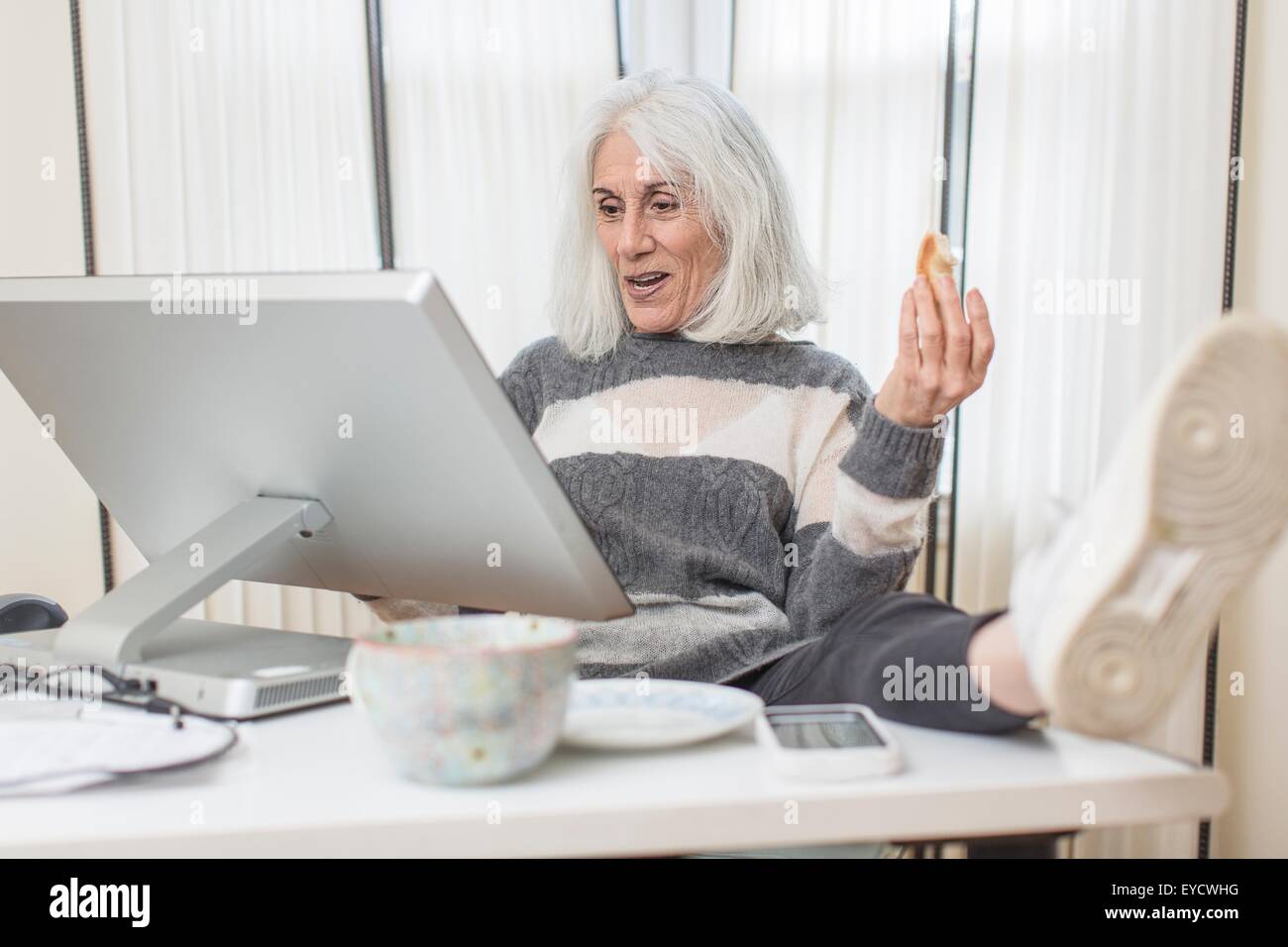 Porträt von senior Frau sitzt am Computer mit Fuß auf Schreibtisch Stockfoto