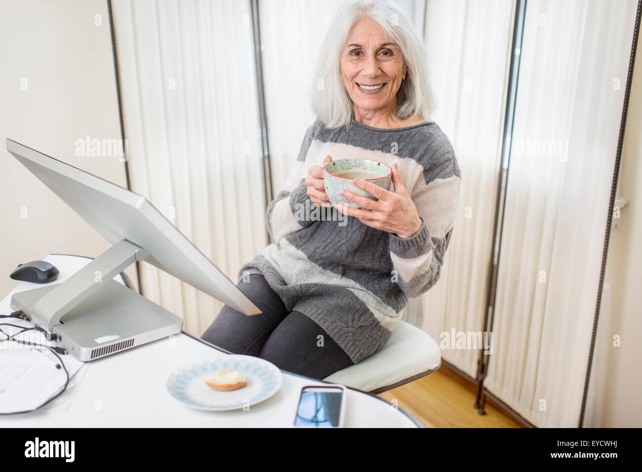 Porträt von senior Frau sitzt am Computer halten Tasse Stockfoto