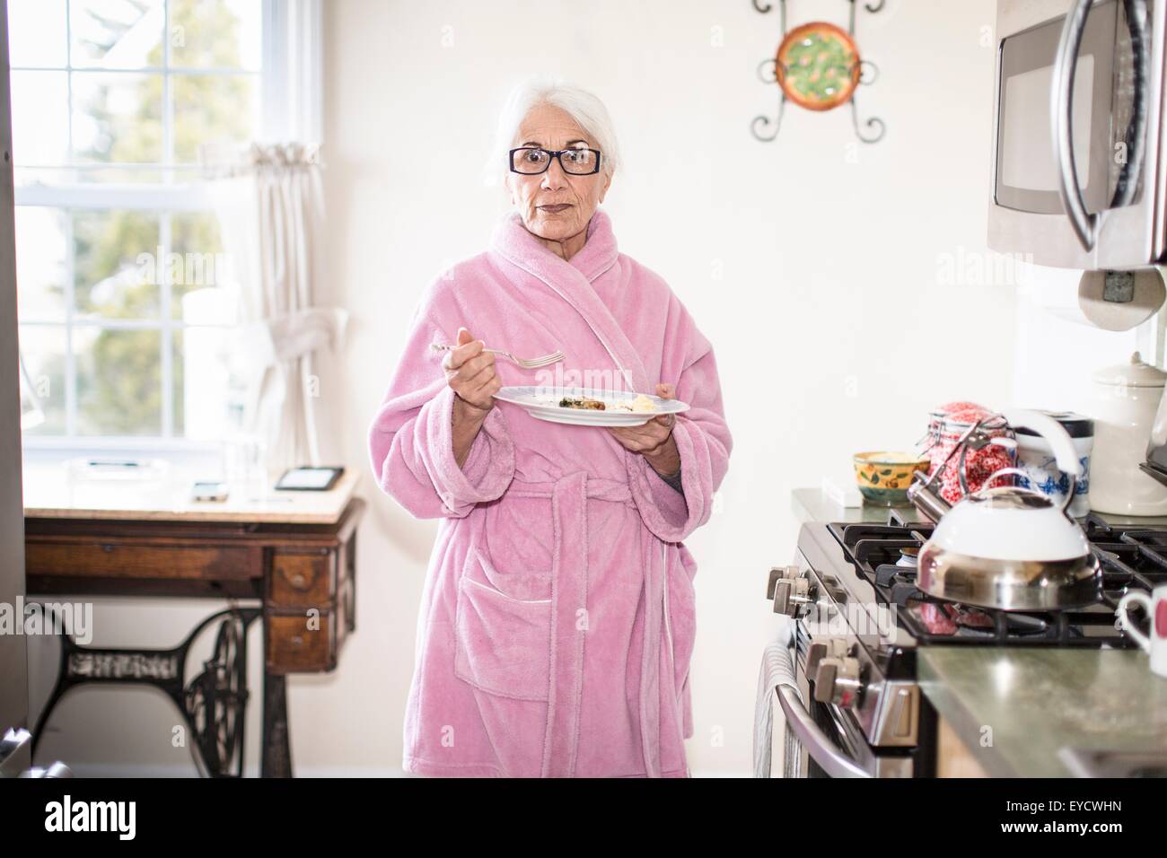 Ältere Frau im Küche hält Teller mit Essen Stockfoto