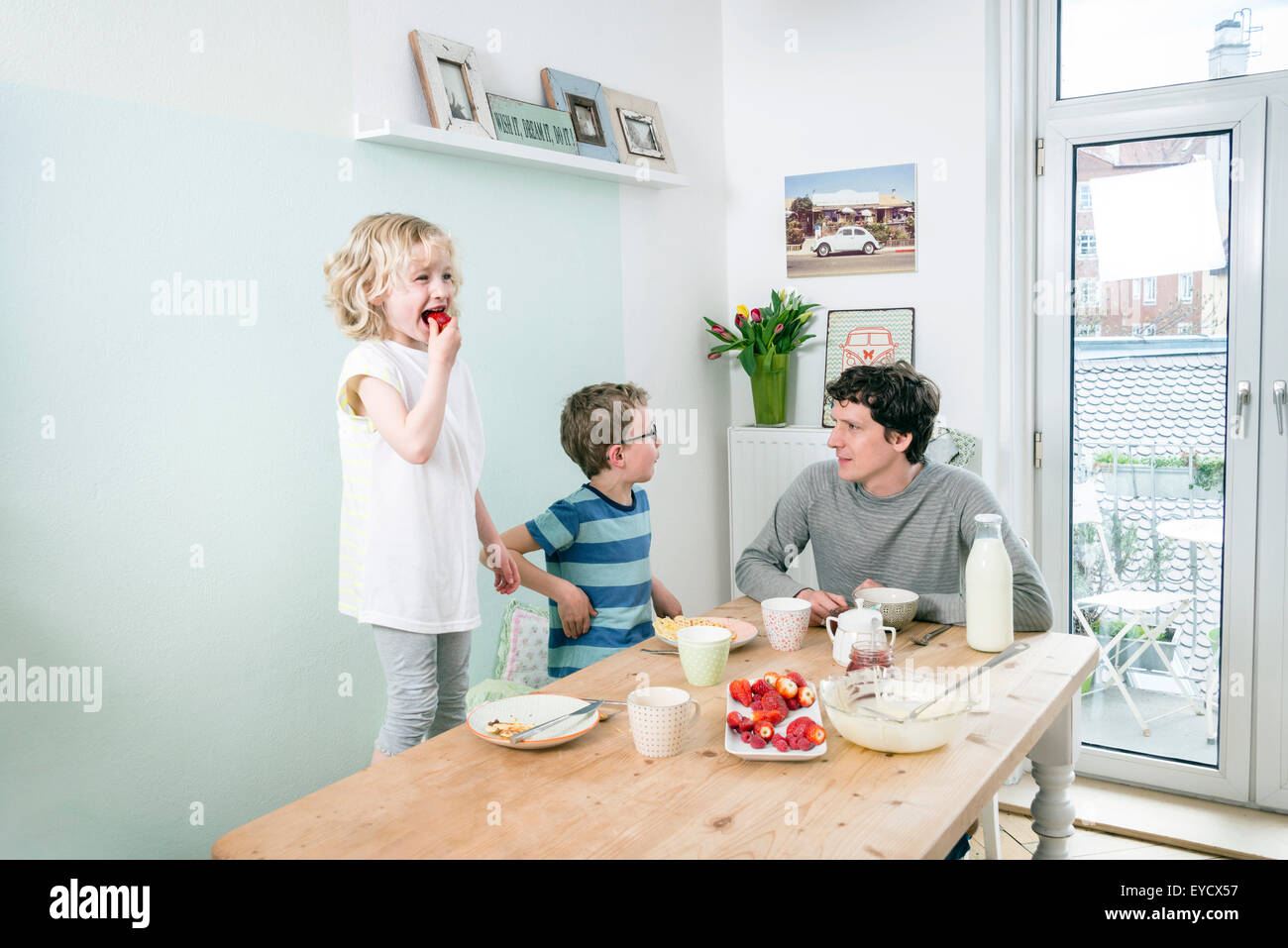 Vater und Kinder essen Waffeln in Küche Stockfoto