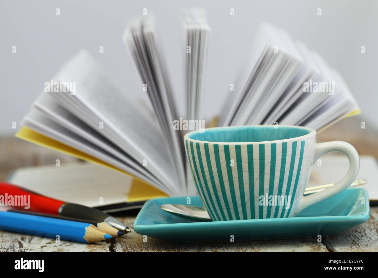 Tasse Kaffee mit offenen Buch im Hintergrund Stockfoto