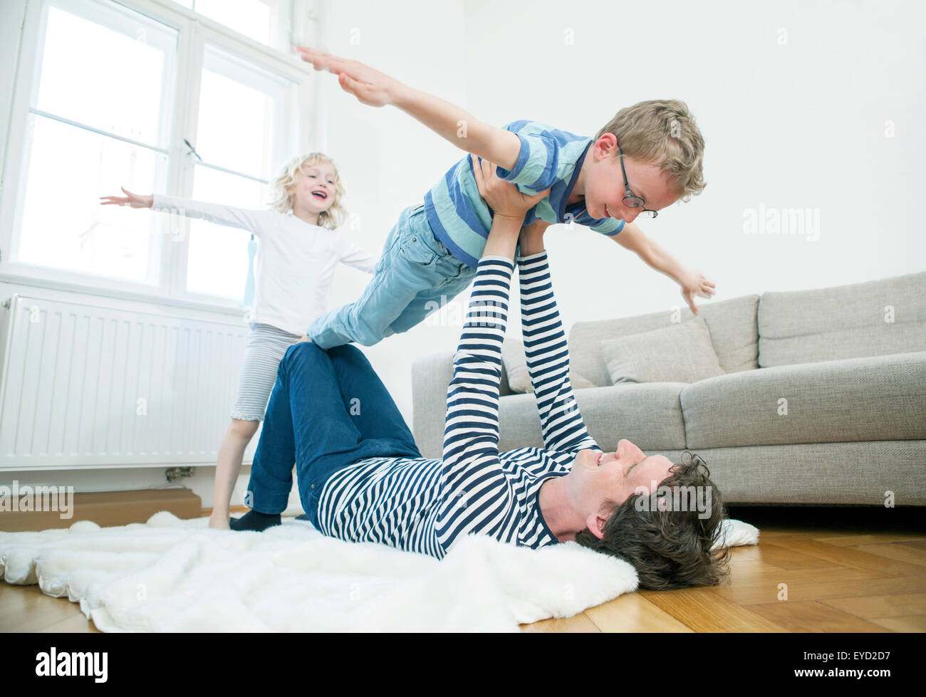 Vater mit zwei Kindern im Wohnzimmer spielen Stockfoto