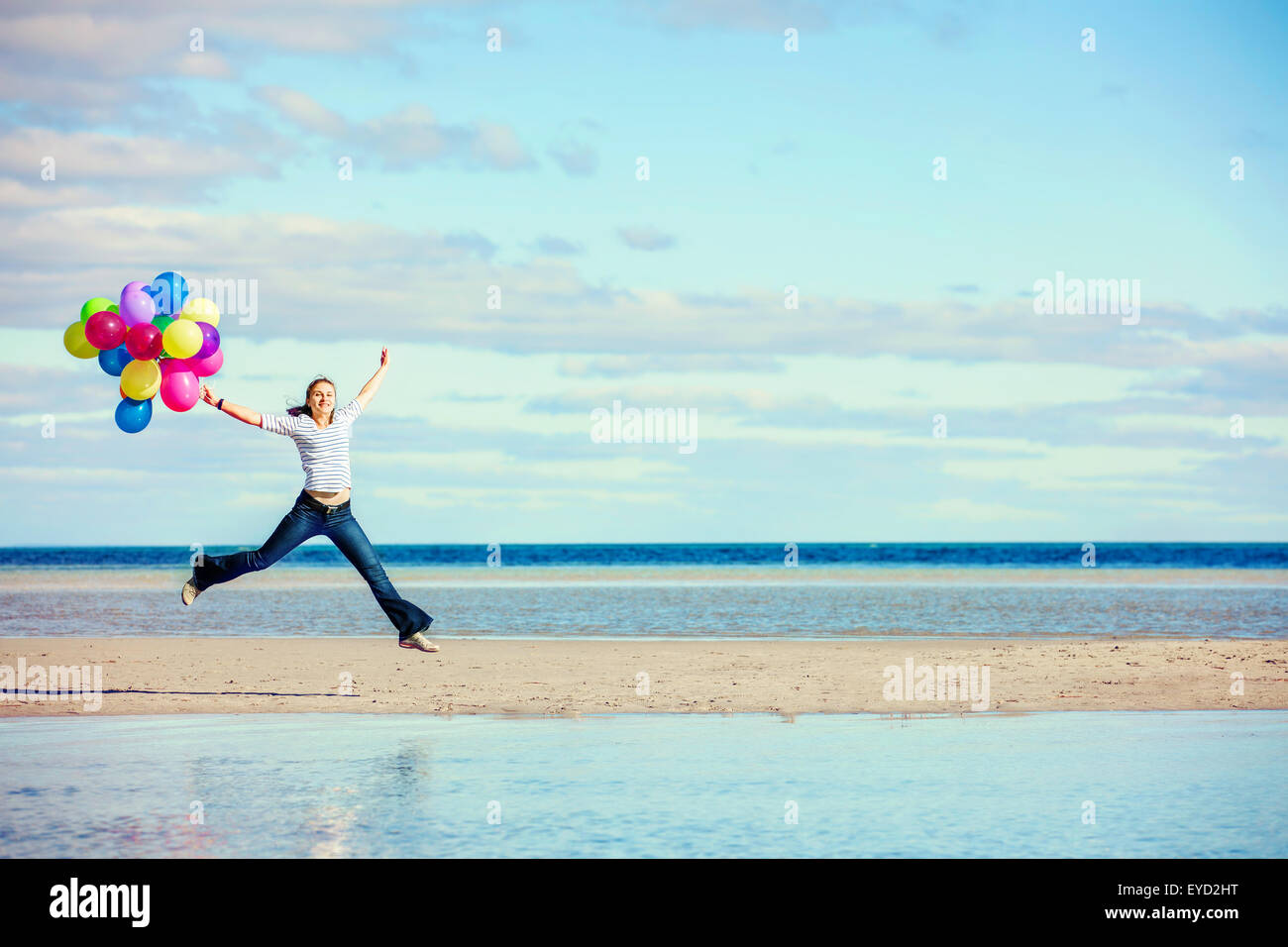 Schöne Mädchen springt am Strand halten Sie farbige Ballons Stockfoto