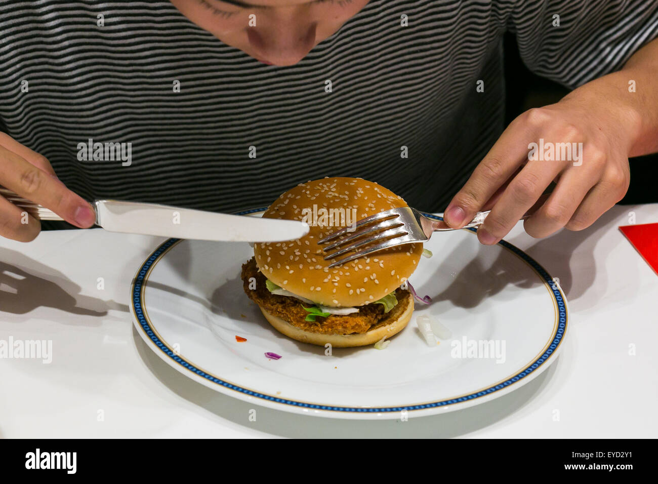 Ein Kunde genießt einen frischen Mac Burger mit Messer und Gabel als Teil  des McDonalds besonderes Abendessen bei einem '' Restaurant M'' Event im  noblen Roppongi Hills Bereich auf 27. Juli 2015,