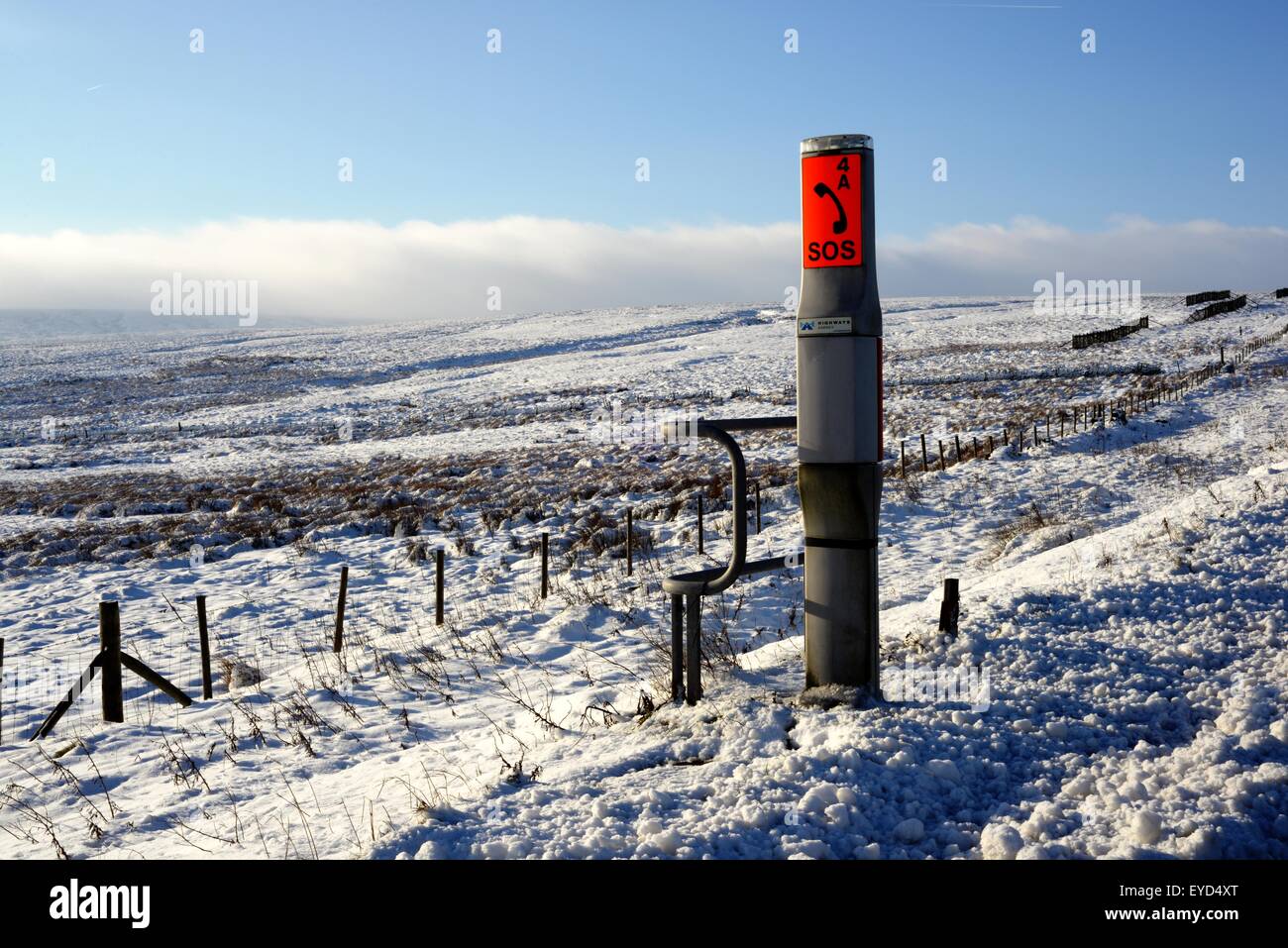 Eine verschneite Szene mit einer SOS-Station am Straßenrand neben dem WOODHEAD Pass A628 in den Pennine Hills, Nordengland. Stockfoto