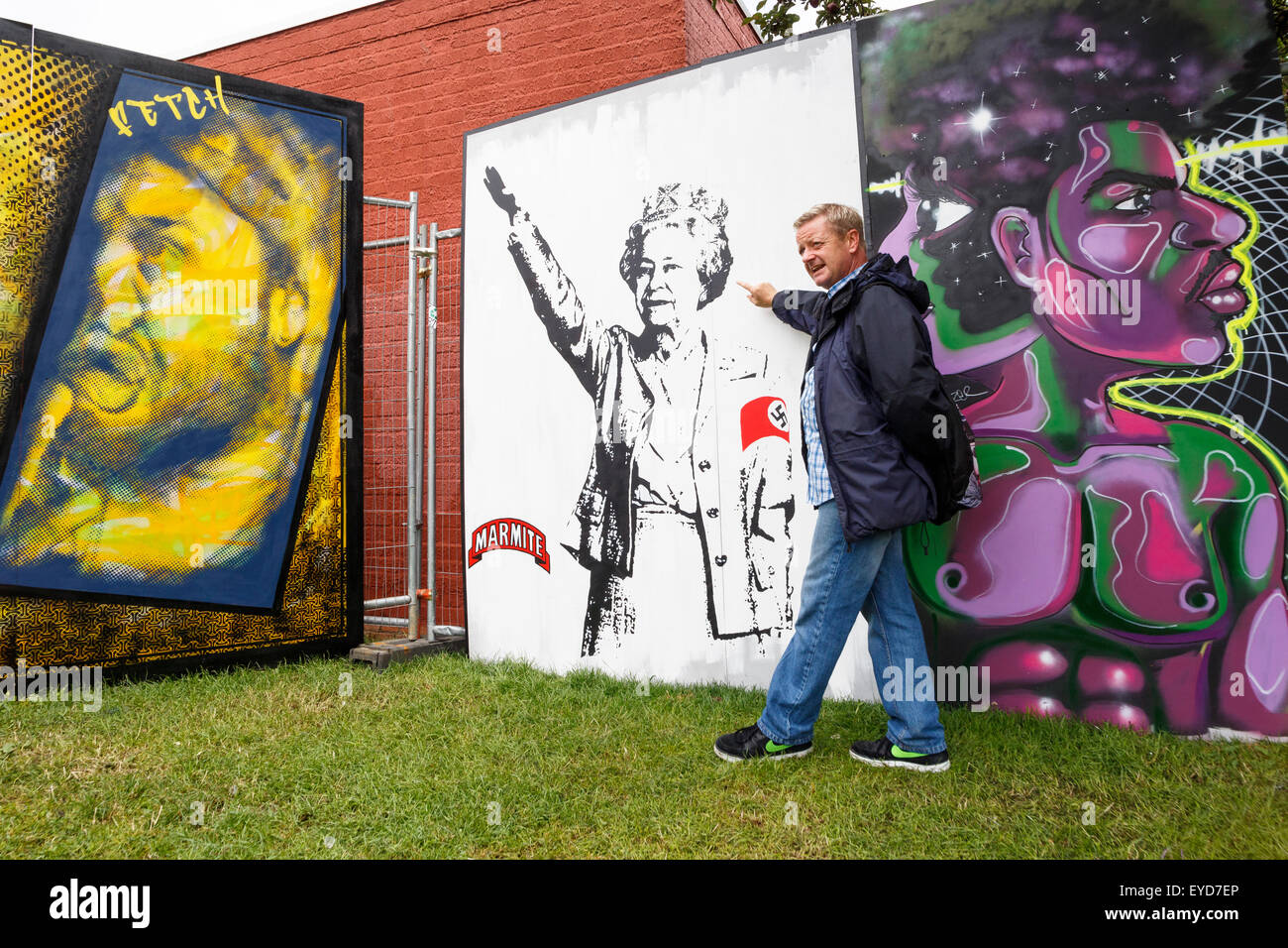 Bristol, Großbritannien, 27. Juli 2015. John Nation ein Reiseleiter von Bristol Street Art Tours wird mit Besuchern gesprochen, während sie ein Kunstwerk in der North Street von T. wat (korrekte Schreibweise) sehen, das die Königin beim Ansprechen eines Nazi-Saluts zeigt. Das Kunstwerk wurde für das Upfest 2015, Europas größtes Street Art & Graffiti Festival, geschaffen. Quelle: Lynchpics/Alamy Live News Stockfoto