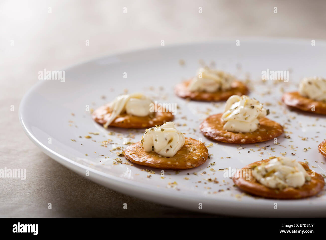 Kräcker mit Frischkäse auf weißen Teller für einen Snack mit oregano Stockfoto