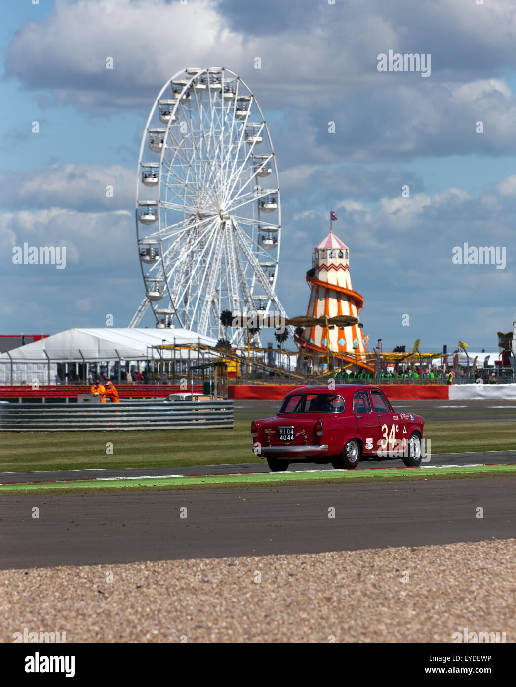 Biegen Sie Geoff Gordon, ein 1961 Alfa Romeo Giulietta Ti, um die Schleife fahren in Silverstone mit der Kirmes dahinter. Stockfoto