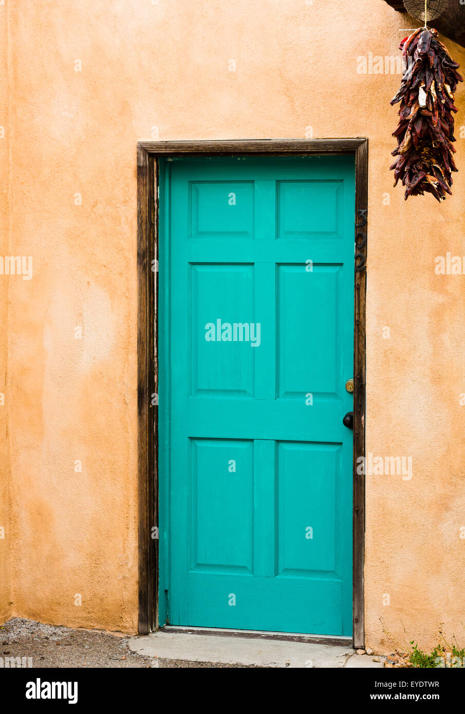 Alten Pueblo spanischen Stil Gebäude mit Adobe Wände verstärkt durch blaue Tür mit hängenden roten Paprika. Stockfoto