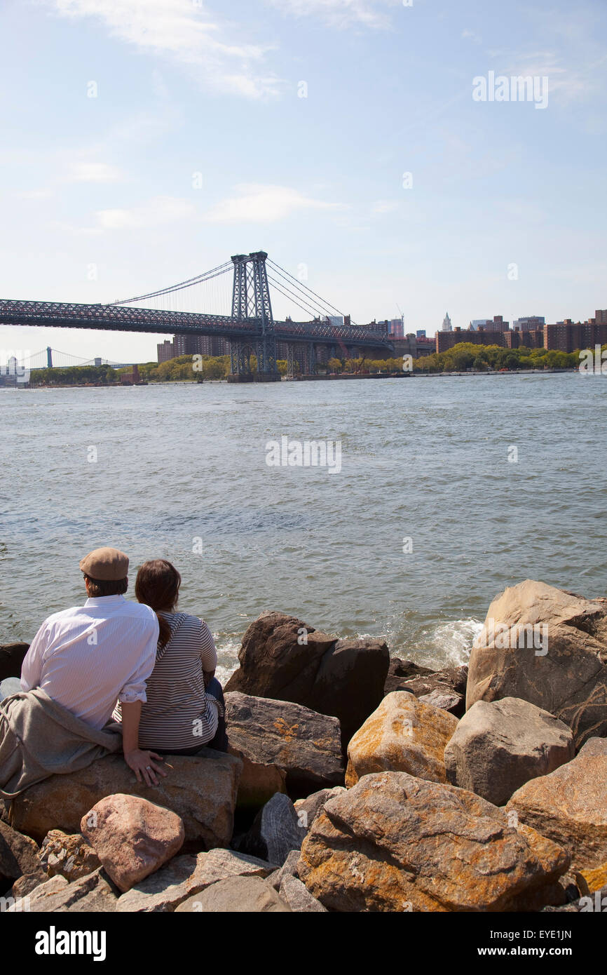 USA, New York State, New York City, Ansichten der Williamsburg Bridge und Manhattan; Brooklyn, paar sitzt am Grand Street Park Stockfoto