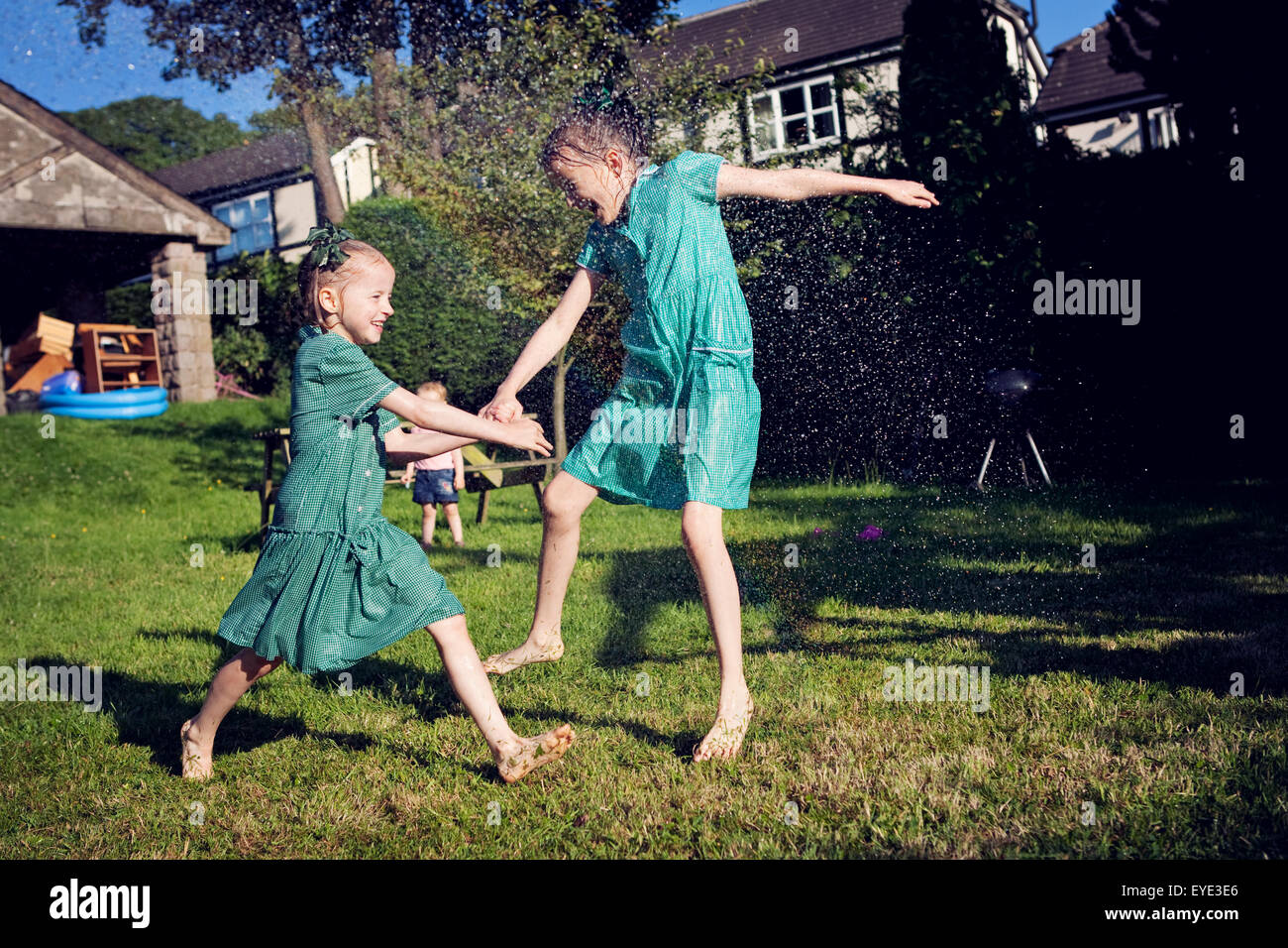 Zwei Kinder in der Schule Sommer Kleider, läuft durch ein Wasser-Sprinkler. Stockfoto