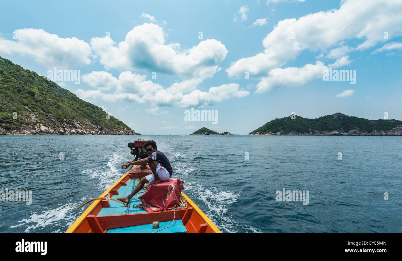 Lokale Mann sitzt am Heck, Lenkung eine Longtail-Boot im türkisfarbenen Meer, Insel Koh Tao Golf von Thailand, Thailand Stockfoto