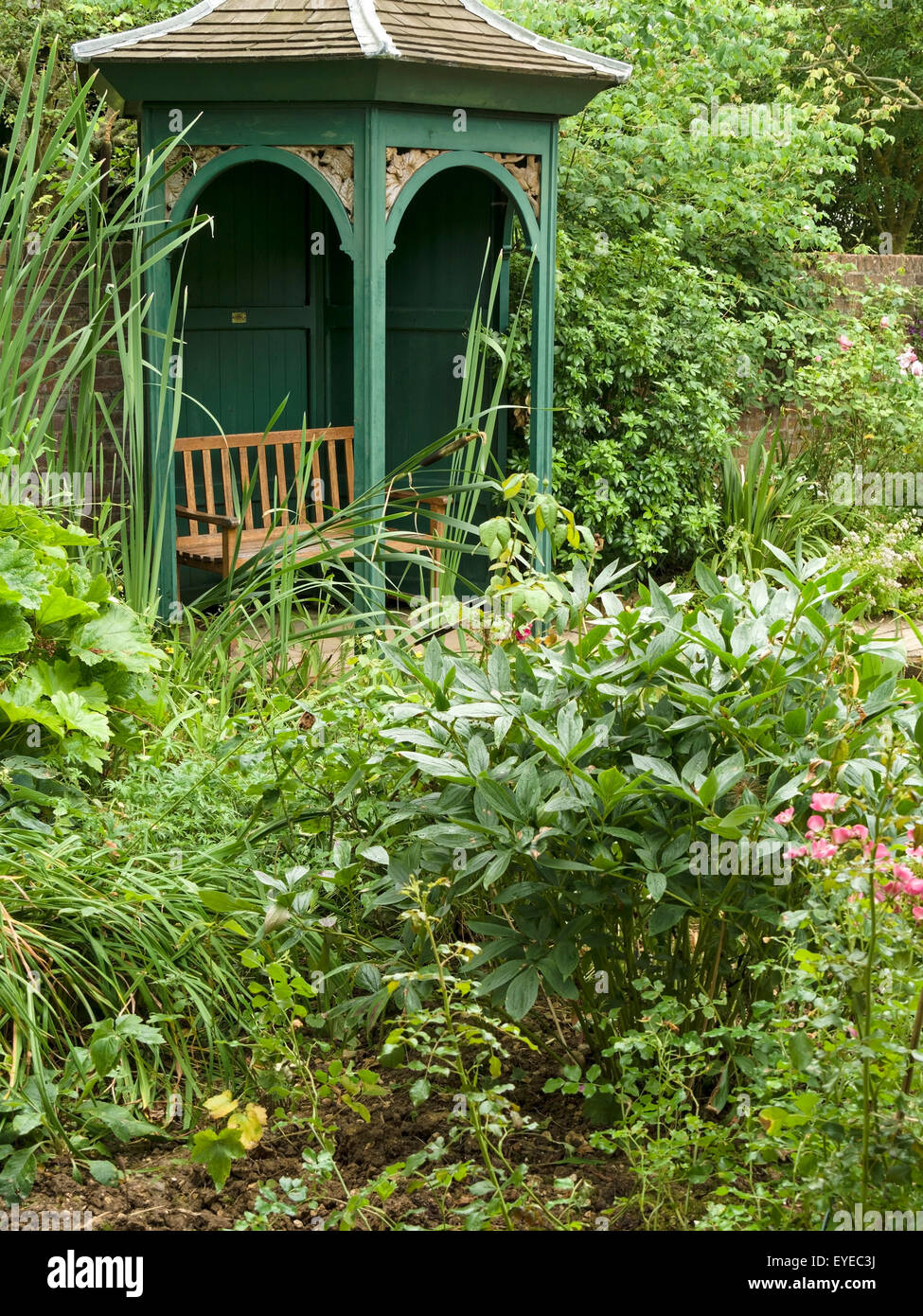 Kunstvoll gewölbte, aus Holz, Garten Pavillon Laube unter überwuchert, grünes Laub, Barnsdale Gärten, Rutland, England, UK. Stockfoto