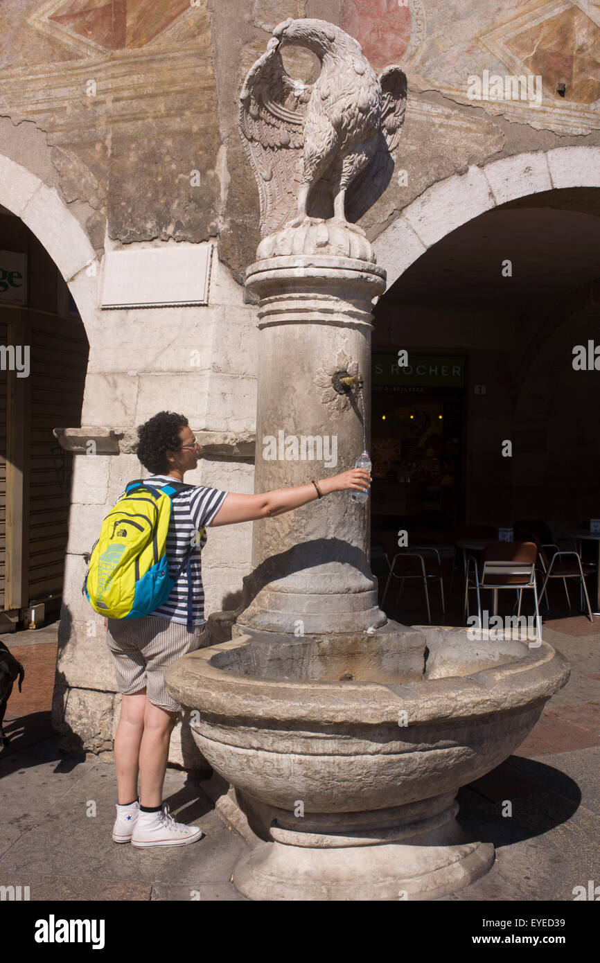 Fresken und Touristen unter frischem Trinkwasser-Brunnen auf der Piazza Duomo, Trient. Stockfoto
