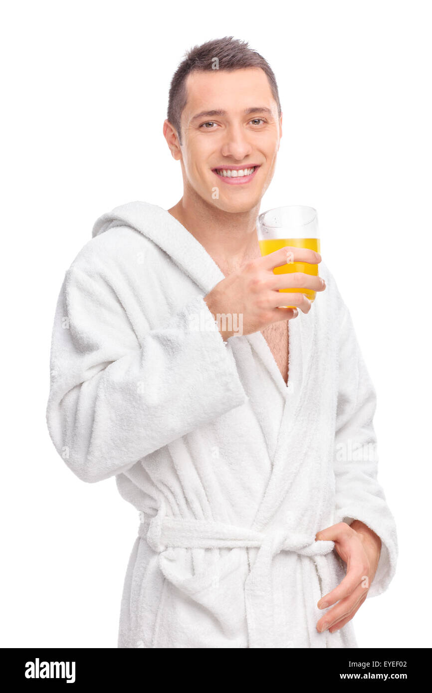 Vertikale Schuss von einem jungen Mann in einem weißen Bademantel hält ein Glas Orangensaft und schaut in die Kamera Stockfoto