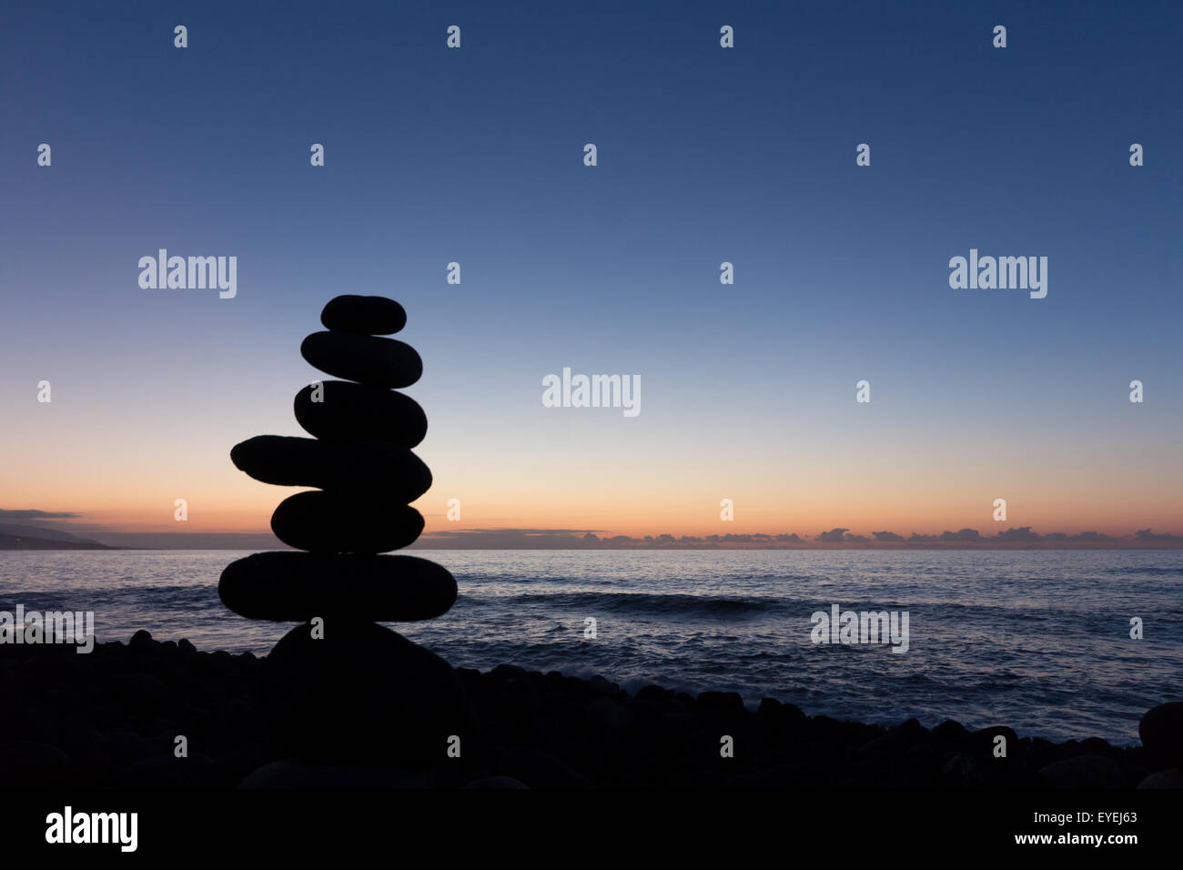 Strand Sonnenuntergang mit gestapelten Steinen silhouette Stockfoto